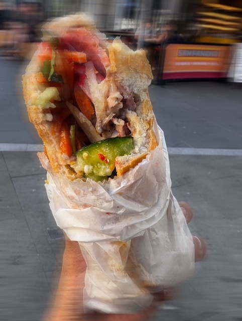 A messy sandwich in motion, background blurred, capturing the rush of grabbing food on the go.