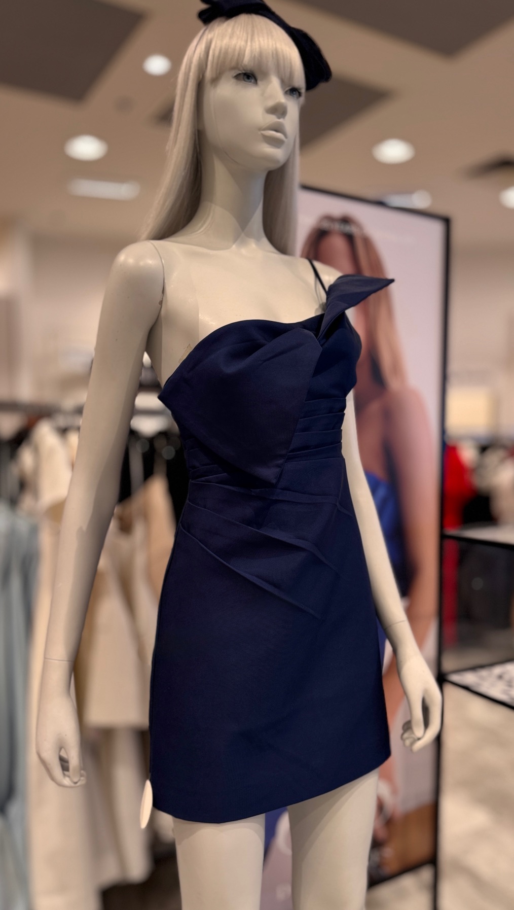 Navy mini-dress with folded sculptural bodice on a mannequin under soft lighting.