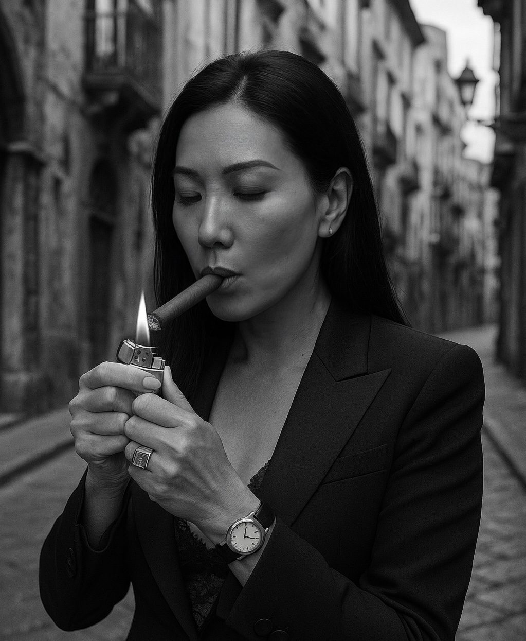 Azura in a dark suit lighting a cigar in a narrow European street, photographed in black and white.