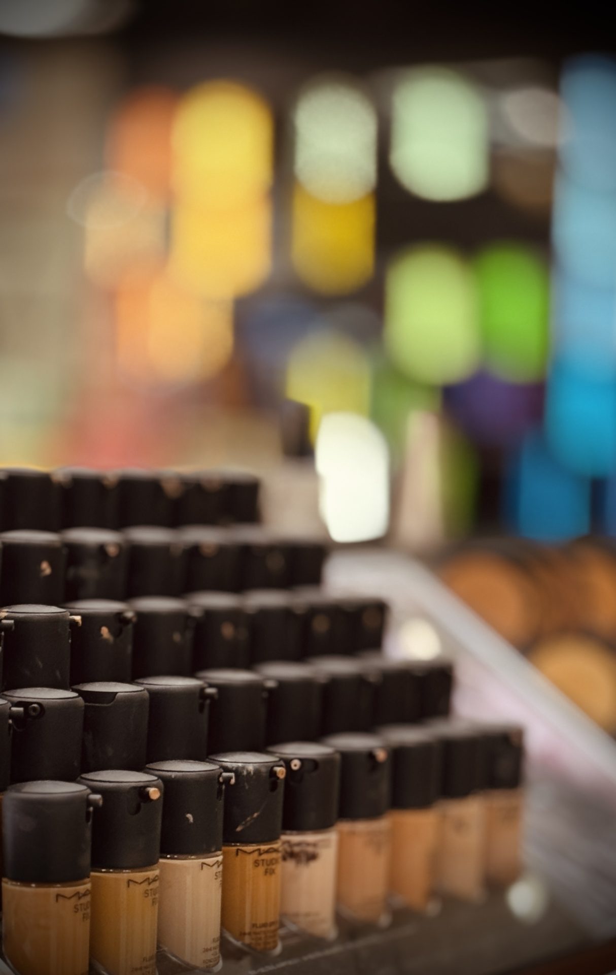 Close-up of foundation bottles arranged by shade on makeup counter.