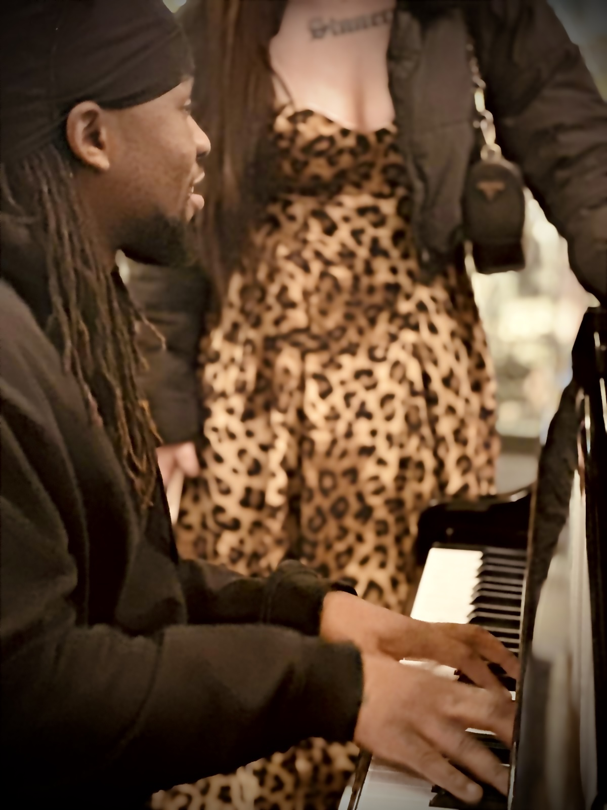 Man playing piano beside woman in leopard dress at QVB.