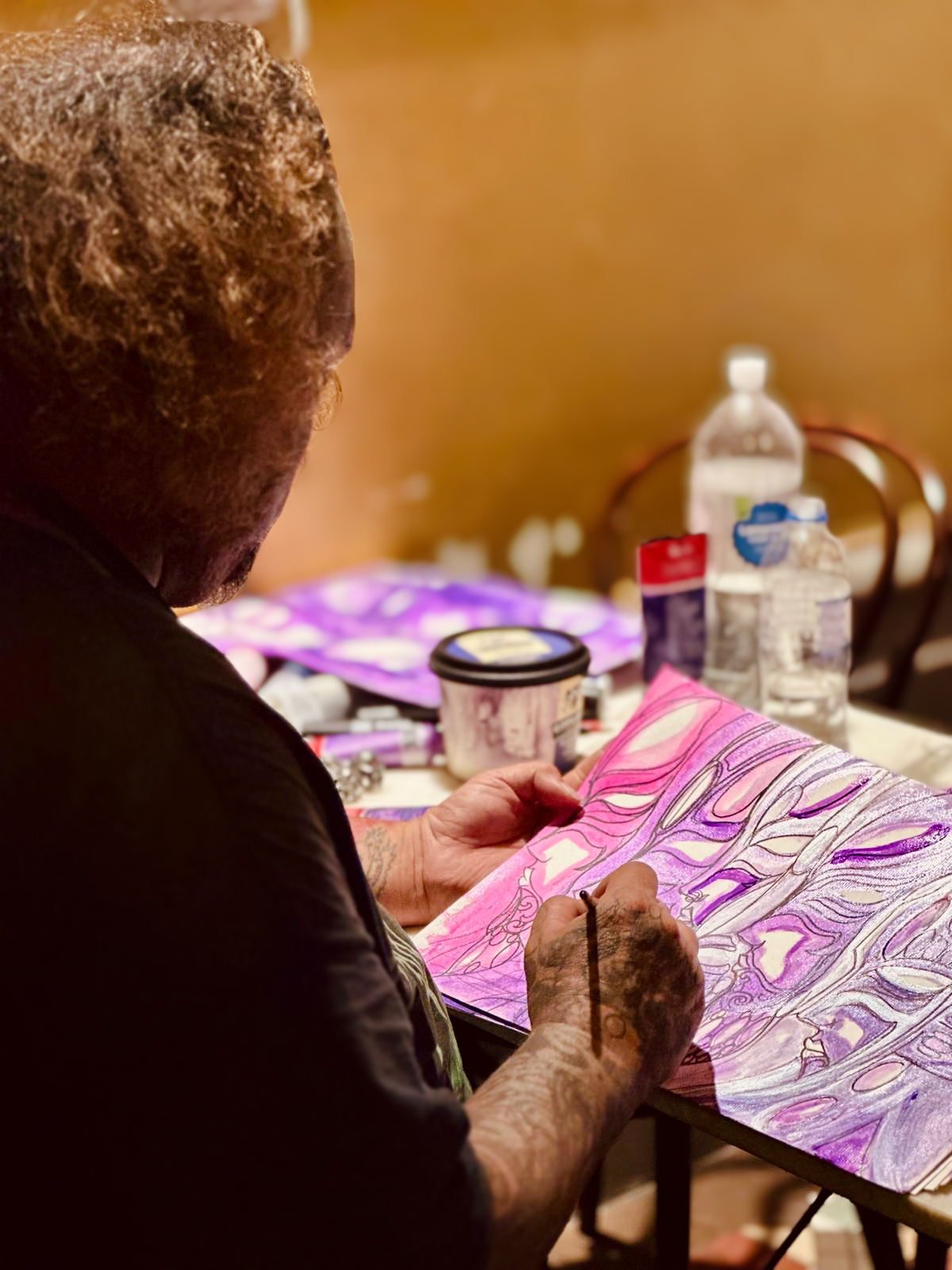 Artist painting on pink and purple feminine faces with watercolour.