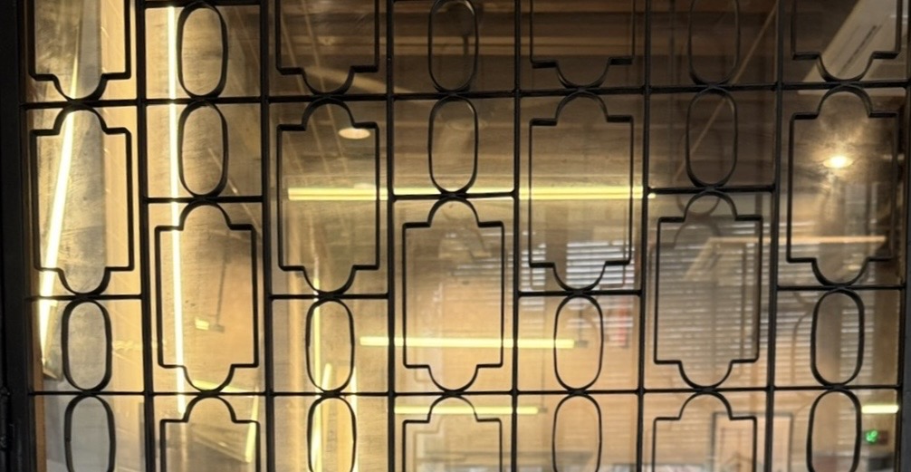 Geometric Chinese lattice window with warm indoor lighting visible through patterned glass.